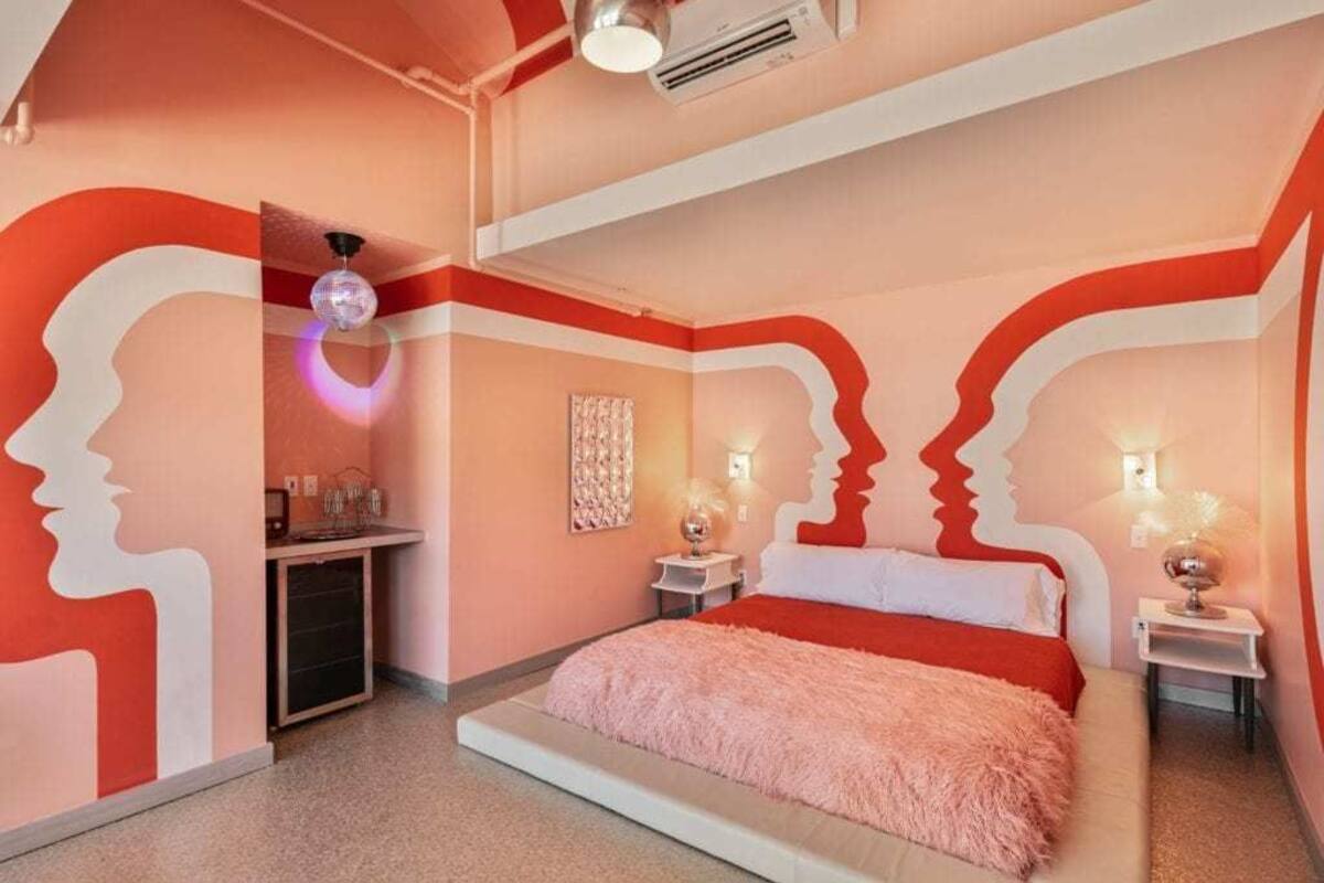 Un dormitorio con cama, cómoda, mesita de noche y pared con diseño rojo y blanco.