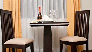 A dining table with two chairs, a bottle of wine, and a plate of food. - Flamante Hotel & Suite (Lima)
