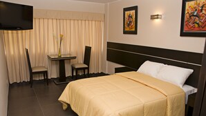A hotel room with a bed, a TV, a table with chairs, and artwork on the walls. - Flamante Hotel & Suite (Lima)