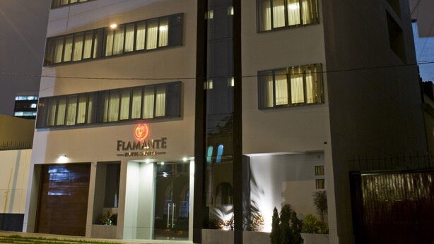 A multi-story building with a prominent red logo on the top. - Flamante Hotel & Suite (Lima)