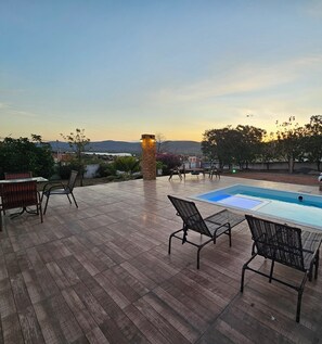 A wooden deck with a pool, outdoor furniture, and a stone pillar. - Pousada Casa Bella (Itaberaba)