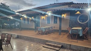 An outdoor patio with wooden flooring, tables with checkered tablecloths, and chairs. - Pousada Casa Bella (Itaberaba)