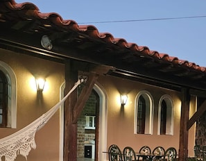 A building with a tiled roof, arched windows, and a hammock. - Pousada Casa Bella (Itaberaba)