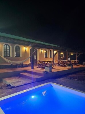 A building with a pool, outdoor seating, and a staircase leading to the entrance. - Pousada Casa Bella (Itaberaba)