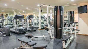 Un gimnasio con cintas de correr, máquinas de pesas y bancos.