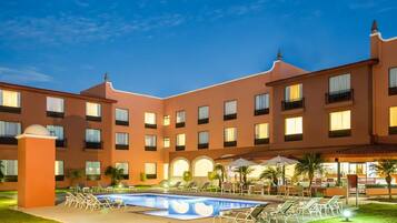 Un hotel con piscina, mobiliario de exterior y un patio.