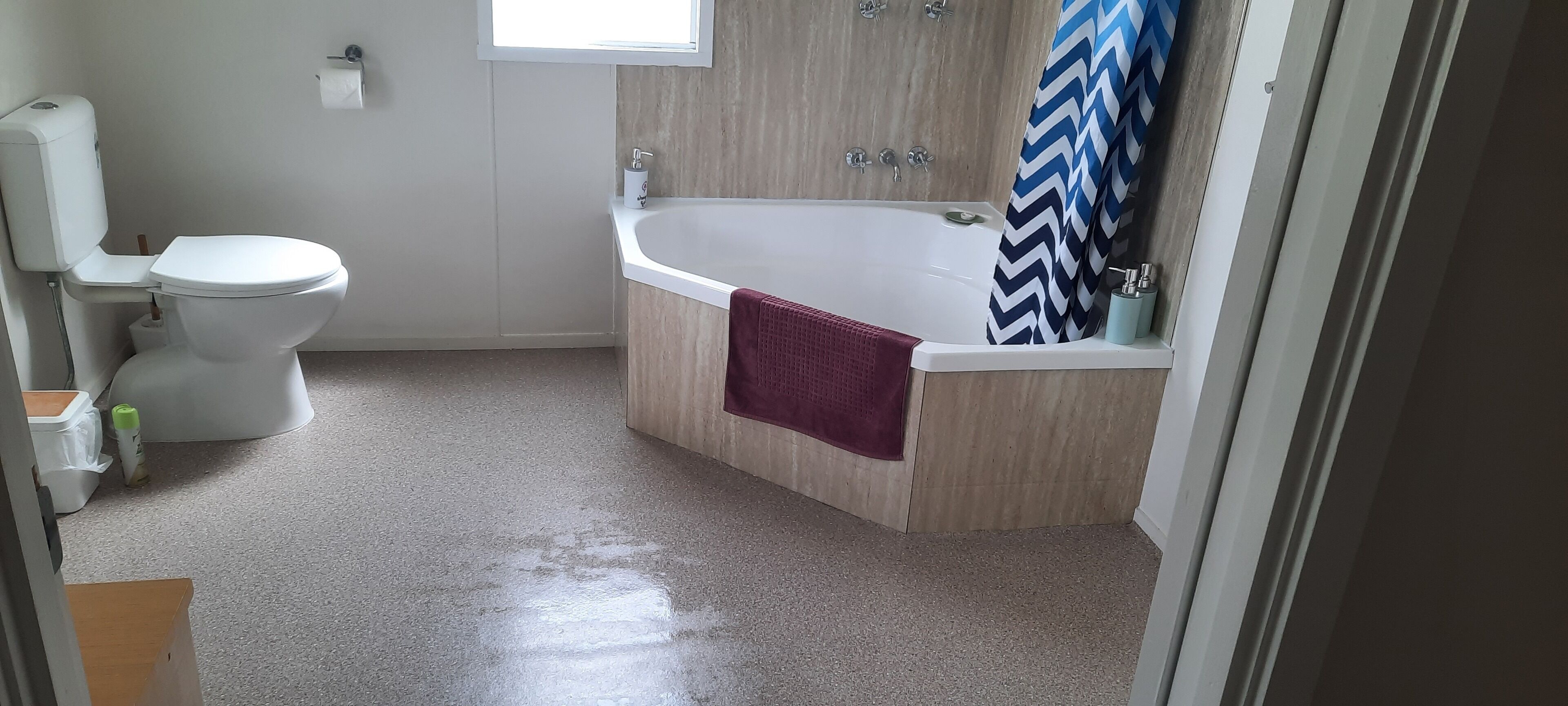 Et badeværelse med toilet, badekar og bruseforhæng.