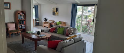 Un salon comprenant un canapé, une table basse, une bibliothèque et un fauteuil.