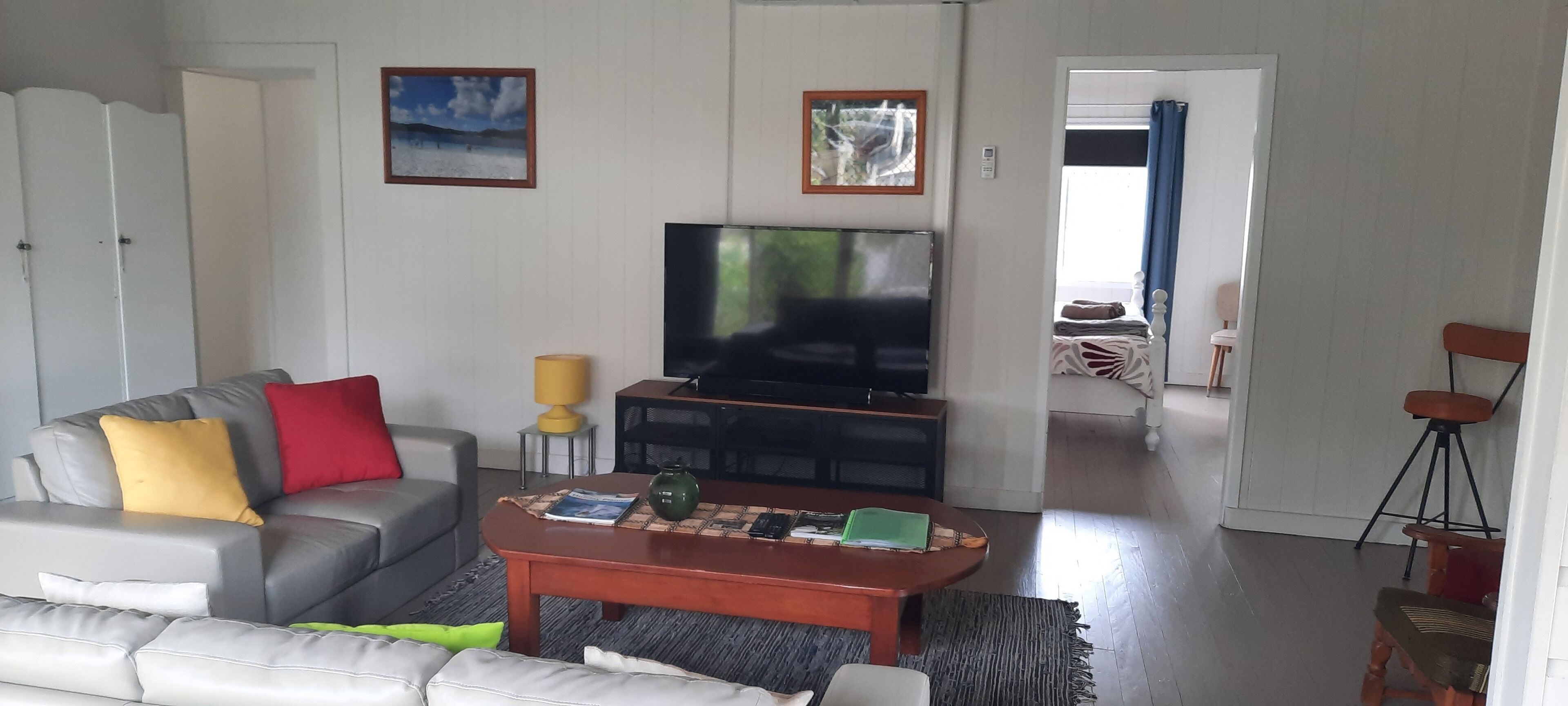 Un salon comprenant un canapé, une table basse, un téléviseur et donnant sur l’extérieur.