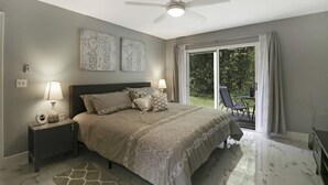 A bedroom with a bed, nightstands, a ceiling fan, and a view of the outdoors. - Completely Renovated 3/2 Close to Disney parks (Kissimmee)