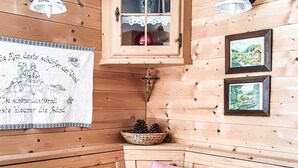 Une pièce chaleureuse aux murs et aux meubles en bois, avec une nappe rouge et un pichet décoratif.