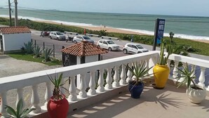 A balcony with a view of the beach and ocean, potted plants, and a sign for the Atlantic Hotel. - Atlantico Hotel (Rio das Ostras)