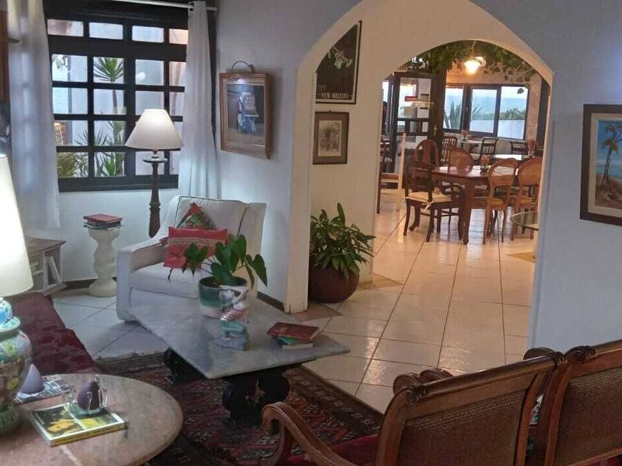 Un rincón acogedor con un sofá, una mesita de centro y una lámpara. Se ve a través de un arco un comedor con una mesa y sillas.