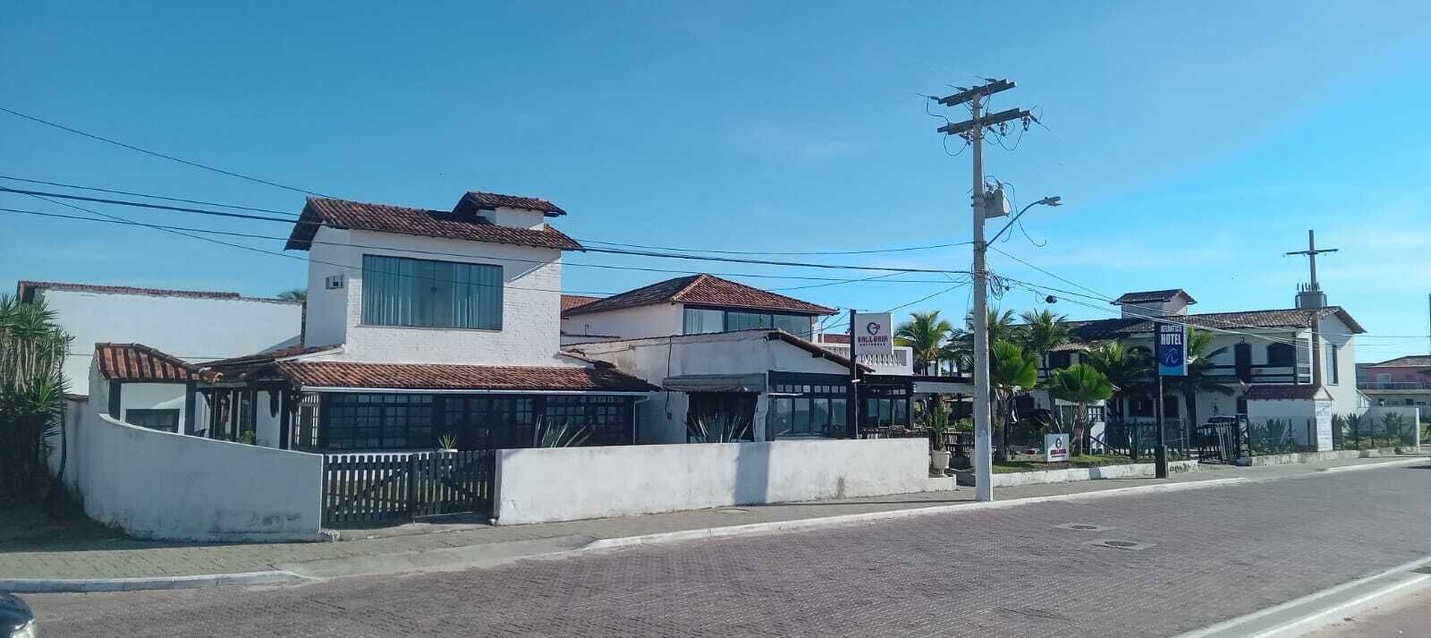 Un hotel con fachada blanca, techo de tejas y entrada protegida por una reja.