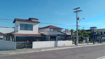 Un hotel con fachada blanca, techo de tejas y entrada protegida por una reja.