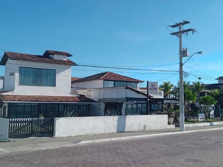 Un hotel con fachada blanca, techo de tejas y entrada protegida por una reja.