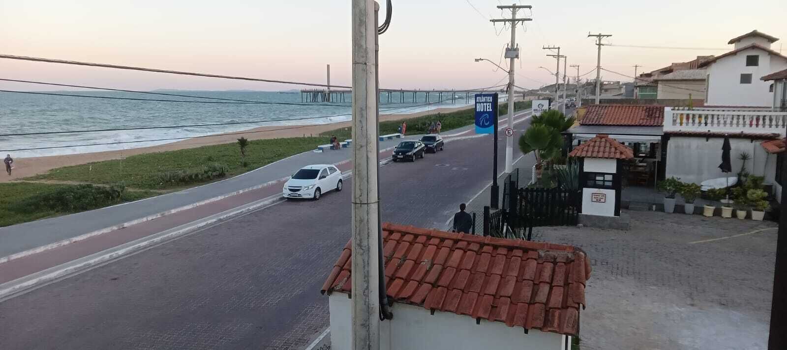 A coastal road with a white car, a pedestrian path, and a hotel named "Atlantic Hotel" in the background.
