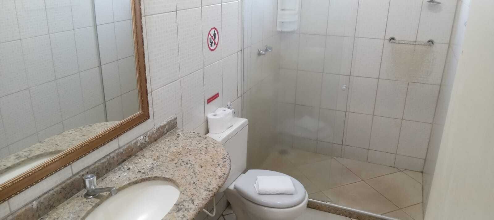 A small bathroom with a sink, toilet, and shower.