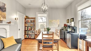 A spacious kitchen with a dining table, chairs, a bookshelf, and a coffee machine.
