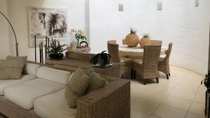 A cozy living area with a sofa, wicker chairs, a dining table with pineapples, and a white wall with a framed picture. - Stunnishing House in Cuernavaca with 20 people accommodation. (Los Limoneros)