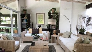 A cozy living room with wicker furniture, a bicycle, and a bookshelf. - Stunnishing House in Cuernavaca with 20 people accommodation. (Los Limoneros)