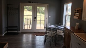 A kitchen with a dining table, chairs, a window, and a door leading outside.
