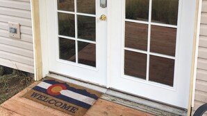 A white double door with a glass panel, a doorbell, and a welcome mat.