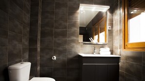 Een moderne badkamer met toilet, wastafel en spiegel.