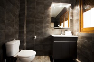 Un baño moderno con inodoro, lavamanos y espejo.