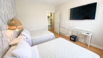 A hotel room with two beds, a TV, a desk with a chair, and a wardrobe.