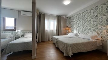 Ein Hotelzimmer mit zwei Betten, einem Fenster mit Vorhängen, einer Wand mit Blattmuster und einer Nachttischlampe.