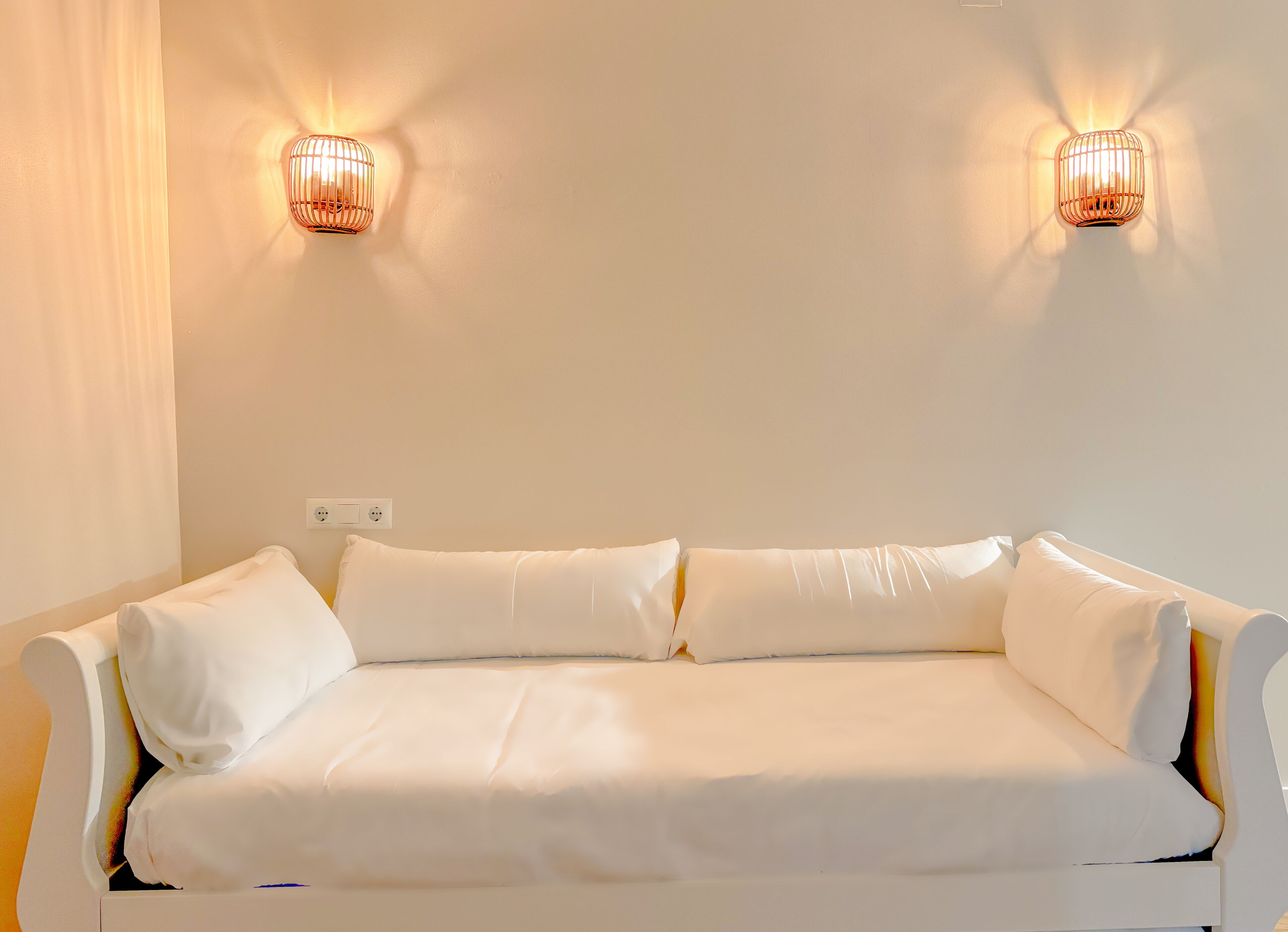 A white sofa with two wall-mounted light fixtures.