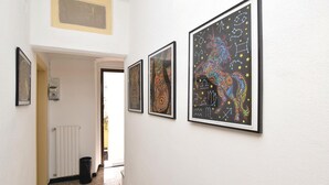 A hallway with three framed artworks on the wall, a radiator, and a trash bin. - 2 bedroom nice apartment in Albenga (Albenga)