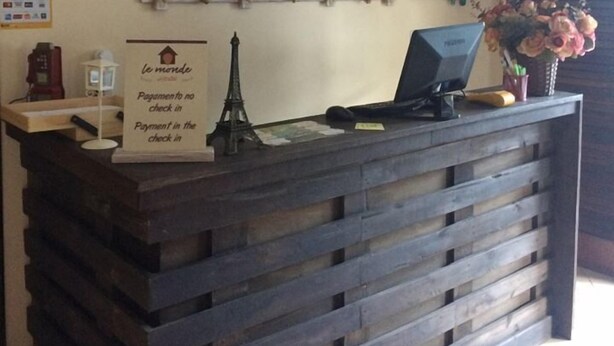 A reception desk with a sign indicating payment is accepted without check-in, a Wi-Fi symbol, and a decorative plant arrangement. - Hostel Le Monde (Angra dos Reis)
