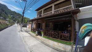 A two-story building with a balcony, a small outdoor seating area, and a visible entrance. - Hostel Le Monde (Angra dos Reis)