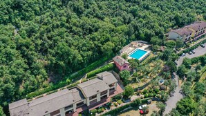 Vista aérea de un edificio de varios pisos con piscina, rodeado de abundante vegetación.