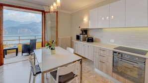 Una cocina moderna con vistas a montañas, un comedor con mesa y sillas, y un ventanal grande.