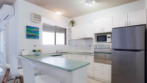 A modern kitchen with white cabinets, a stainless steel refrigerator, a microwave, and a sink. - Kiah 8, 53 Victoria Parade - Stunning water views, Wifi & Air Con (Nelson Bay)