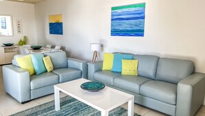 A living room with two light grey sofas, a white coffee table, and a blue painting on the wall. - Kiah 8, 53 Victoria Parade - Stunning water views, Wifi & Air Con (Nelson Bay)