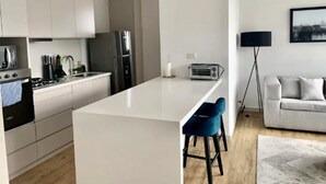 A modern kitchen with white cabinetry, a central island, and bar stools. - Urban Studios by Velvet Luxury (Medellín)
