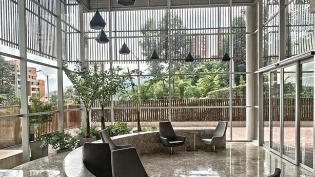 A modern indoor space with a curved seating area, large windows, and hanging pendant lights. - Urban Studios by Velvet Luxury (Medellín)