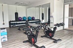 A gym with exercise bikes, dumbbells, and exercise balls.