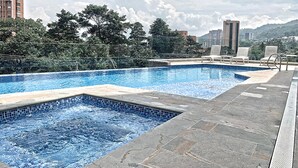 A swimming pool with tiled edges, surrounded by stone tiles and a metal fence. - Urban Studios by Velvet Luxury (Medellín)