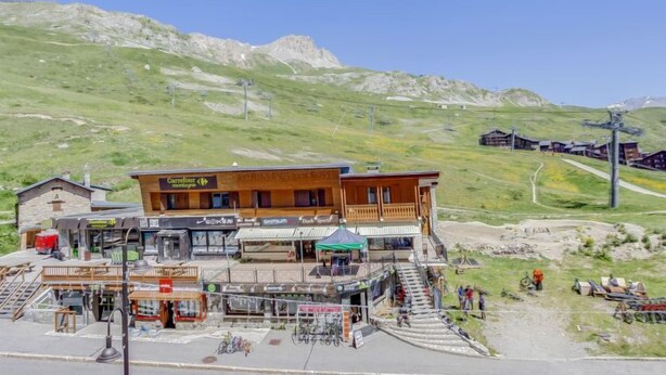 Un complejo turístico de montaña con un edificio de madera que alberga tiendas y un restaurante.