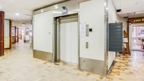 Un ascensor en un pasillo con suelo de baldosas y un letrero que dice "am elevator".