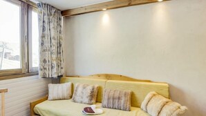 Una habitación acogedora con una cama de madera, una ventana con cortinas estampadas y vistas al exterior.