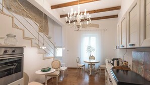 A kitchen with wooden beams, a chandelier, and a dining area with chairs and a table. - Le Nicchie luxury rooms (Lecce)