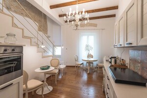 Una cocina con vigas de madera, una araña y un comedor con sillas y una mesa.