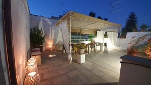 An outdoor patio area with a covered seating area, potted plants, and a fire feature. - Le Nicchie luxury rooms (Lecce)