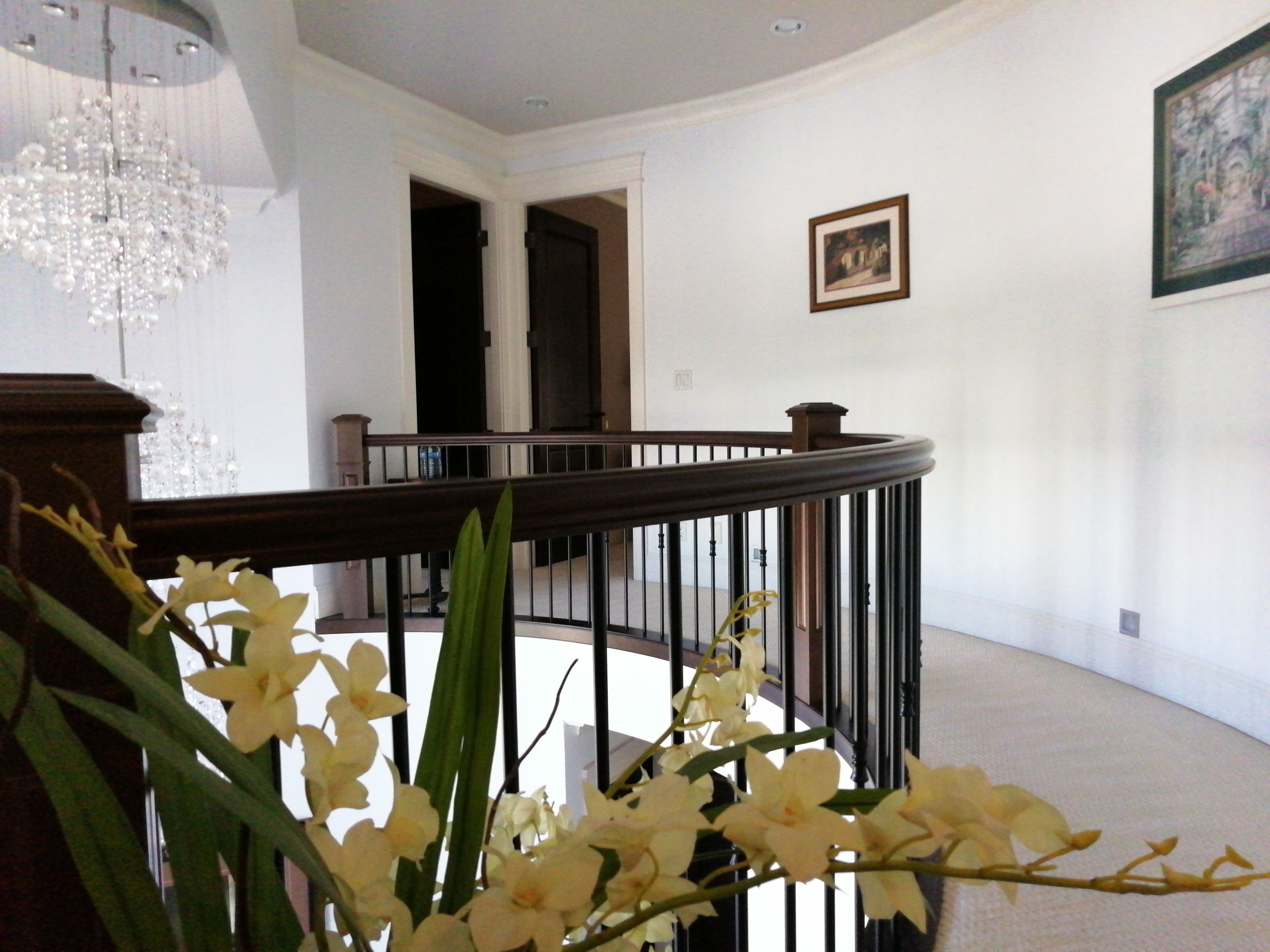 A grand staircase with a wooden handrail and black balusters, leading to an upper floor.